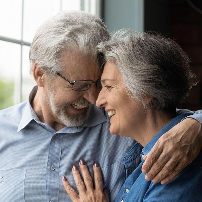 older couple embracing and smiling in house